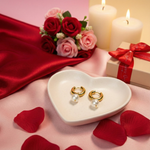 Load image into Gallery viewer, Heart-shaped dish with gold hoop earrings on a pink fabric background with roses and candles.
