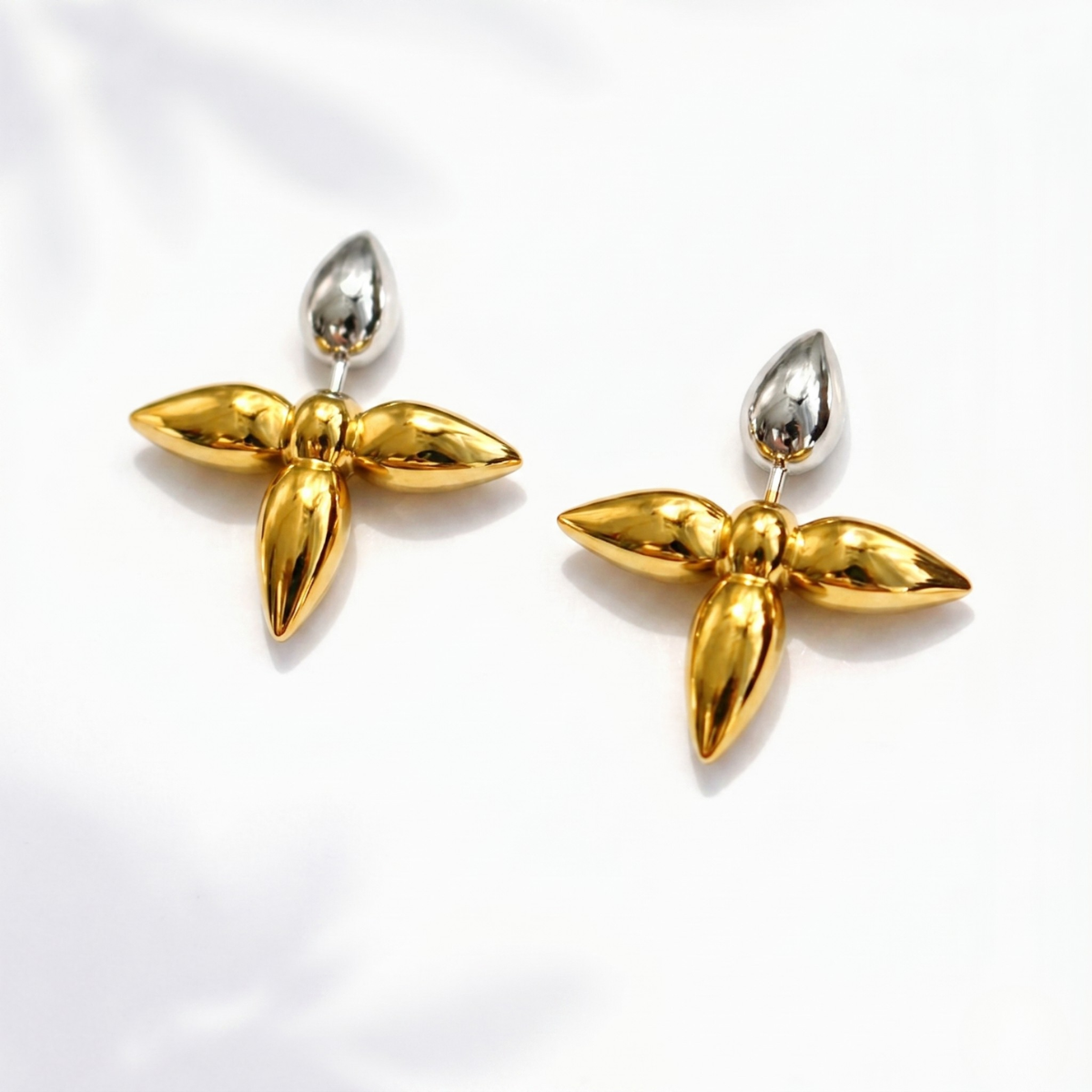 Gold and silver leaf shaped earrings on a white background